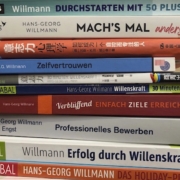 A stack of books by Hans-Georg Willmann in various languages, focusing on self-confidence, willpower, and career development.